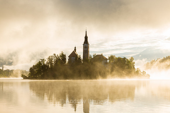 The Church of the Assumption on an island in the middle of Lake Bled, Slovenia, is shrouded in mist as the sun rises